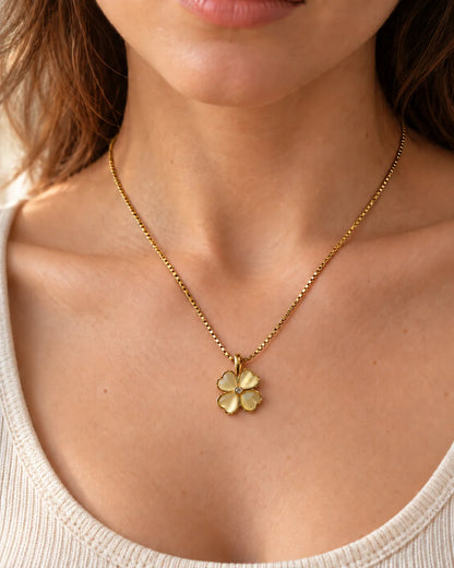 Model wearing the Primrose four-petal heart clover necklace with an ivory scoop-neck top