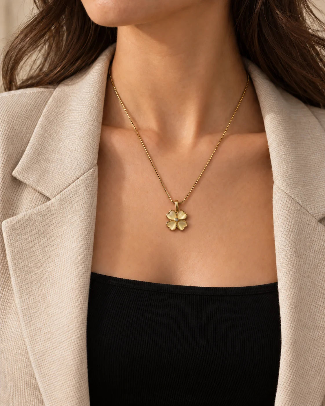 Model in a beige blazer wearing the dainty Primrose clover necklace