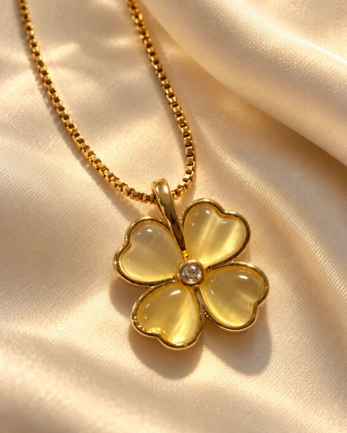 Primrose four-petal clover pendant on cream satin in warm light