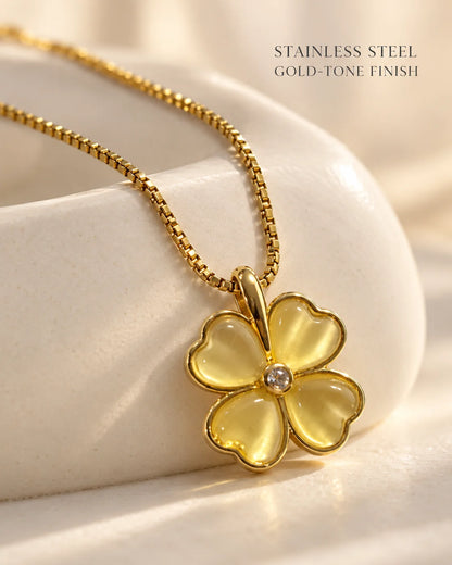 Stainless steel, gold-tone finish: Primrose clover necklace draped over an ivory dish