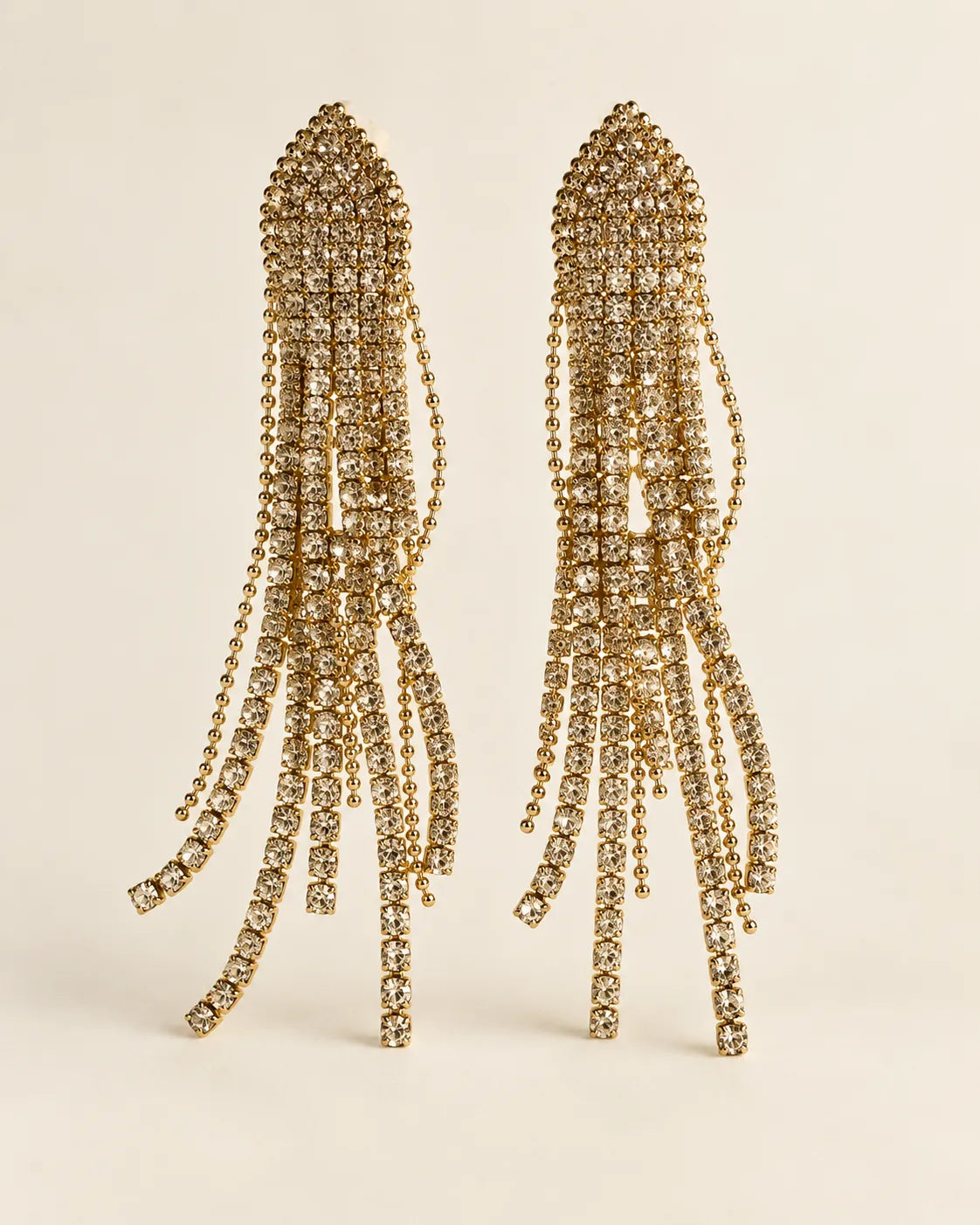Long white rhinestone tassel drop earrings on a cream background