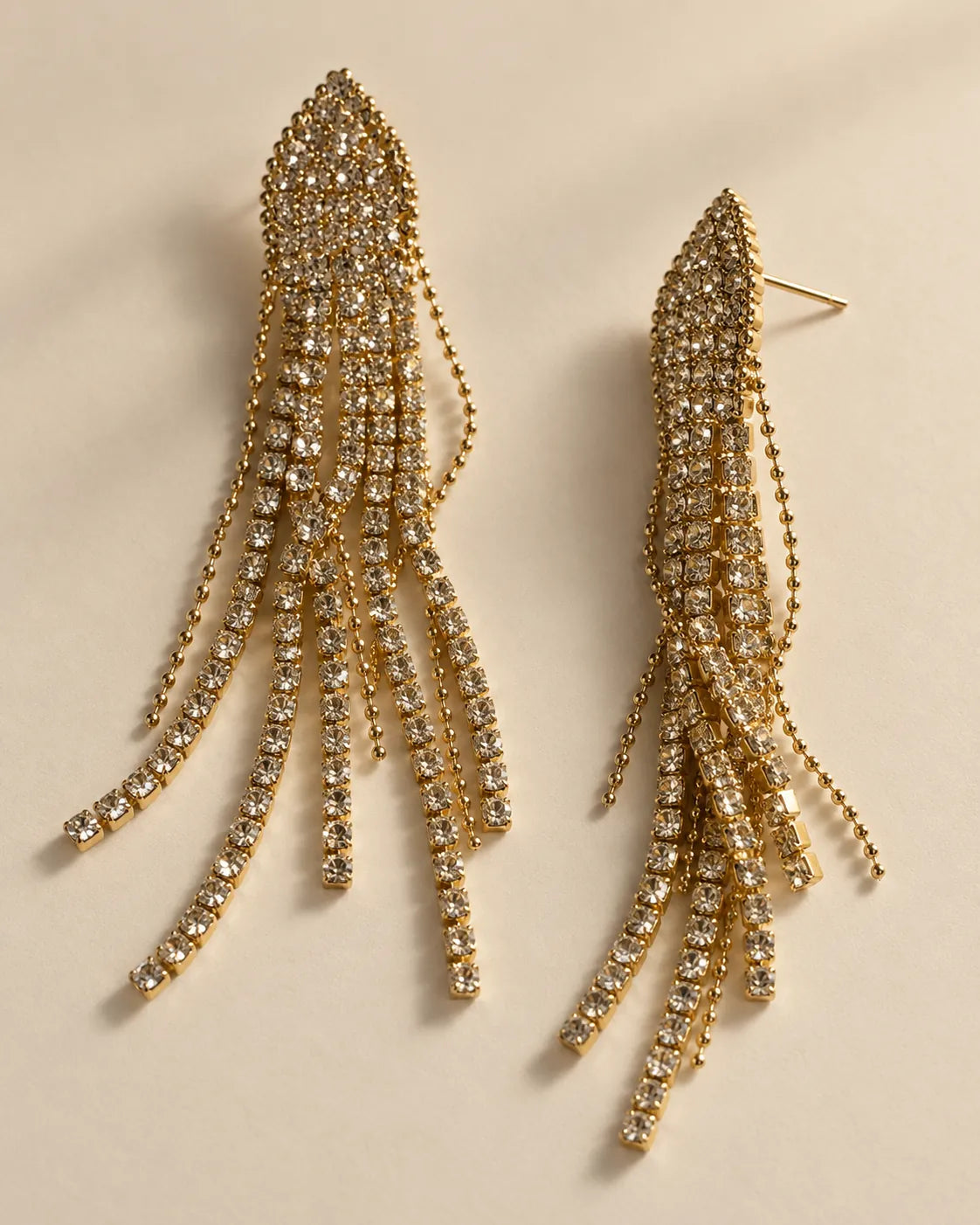 Angled view of the gold-tone rhinestone tassel earrings showing the post