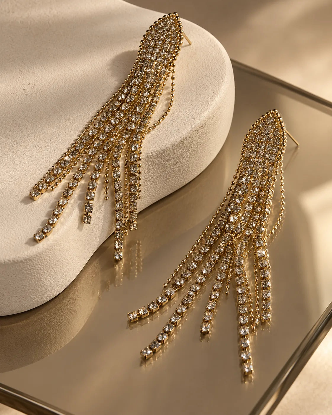 Rhinestone tassel drop earrings on a mirrored surface