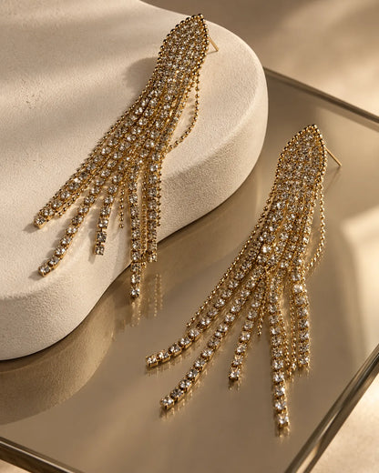 Rhinestone tassel drop earrings on a mirrored surface