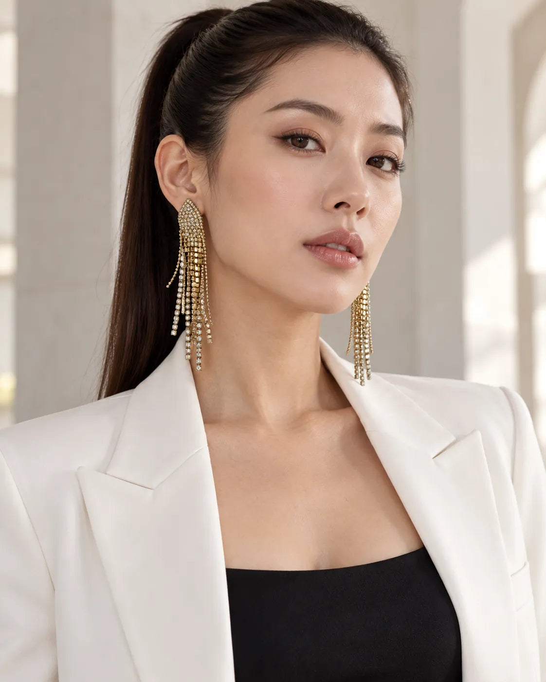 Model in a white blazer with a high ponytail wearing the tassel earrings
