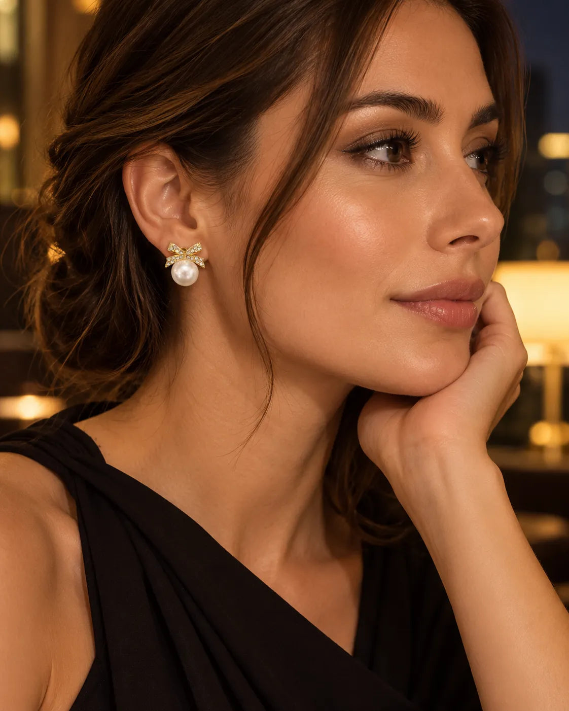 Model in a black top wearing the gold rhinestone bow pearl-look earrings