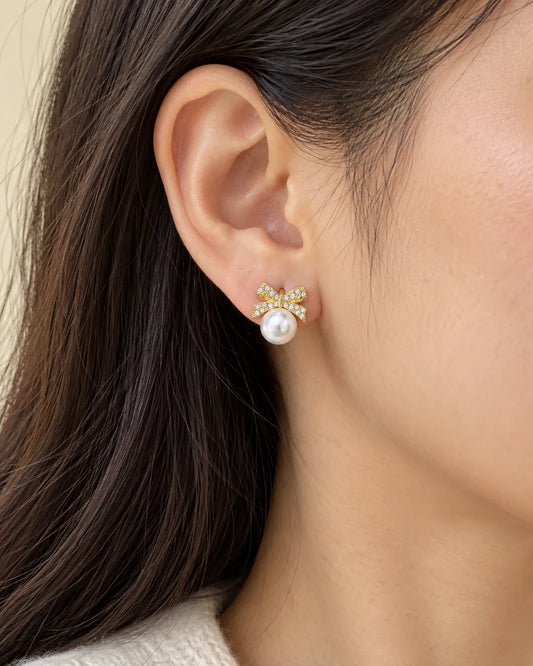 Close-up of the gold bow and pearl-look stud worn on the ear
