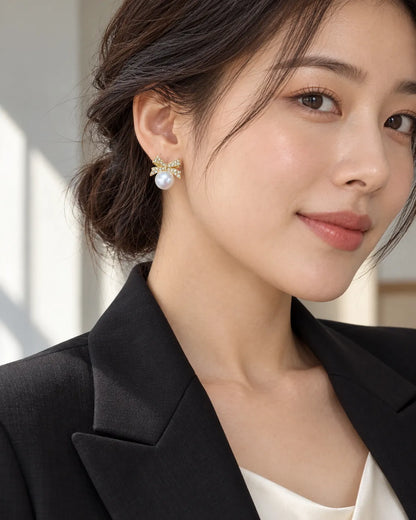 Model in a black blazer wearing the gold bow and pearl-look studs