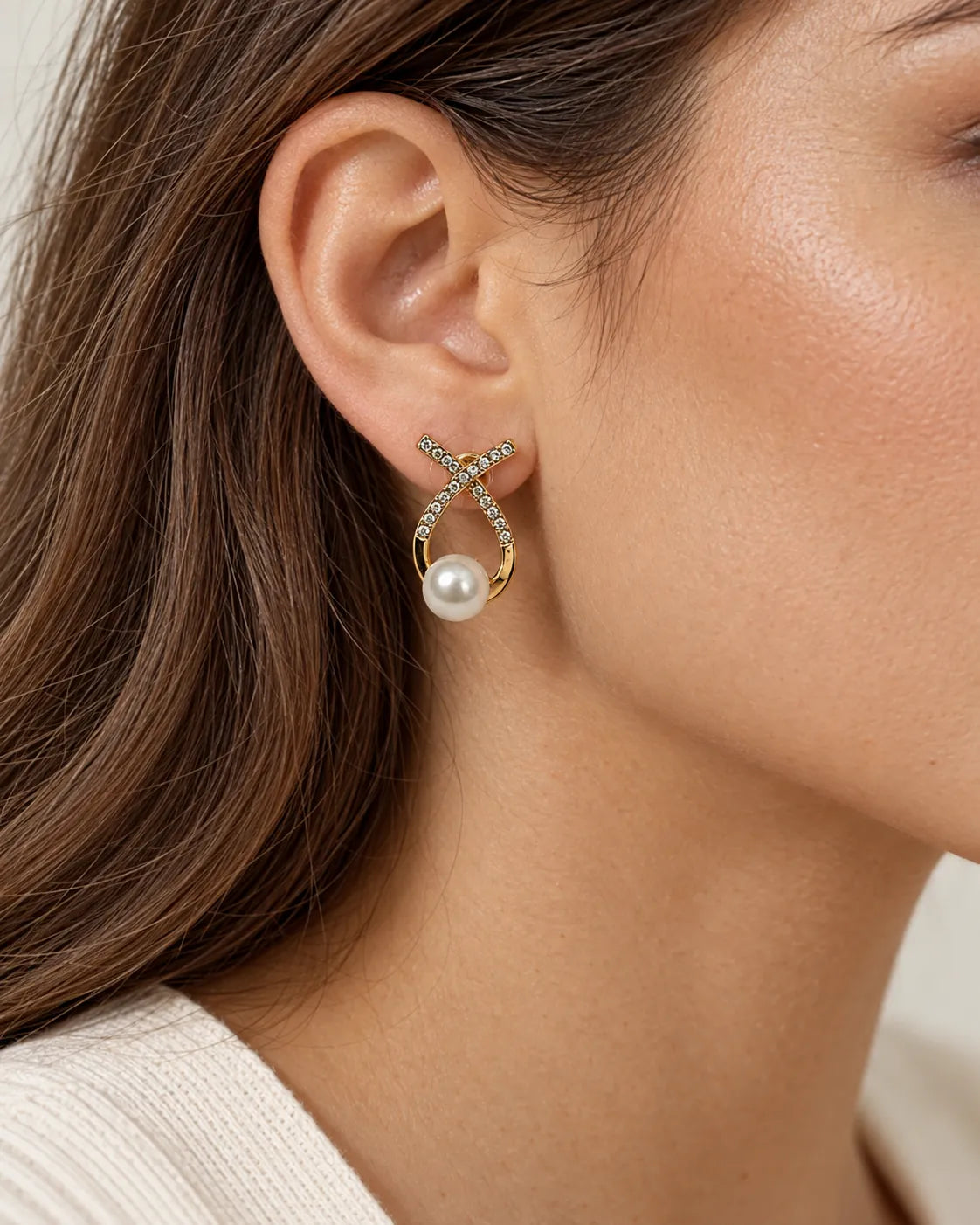 Close-up of the gold crossed loop pearl-look stud worn on the ear