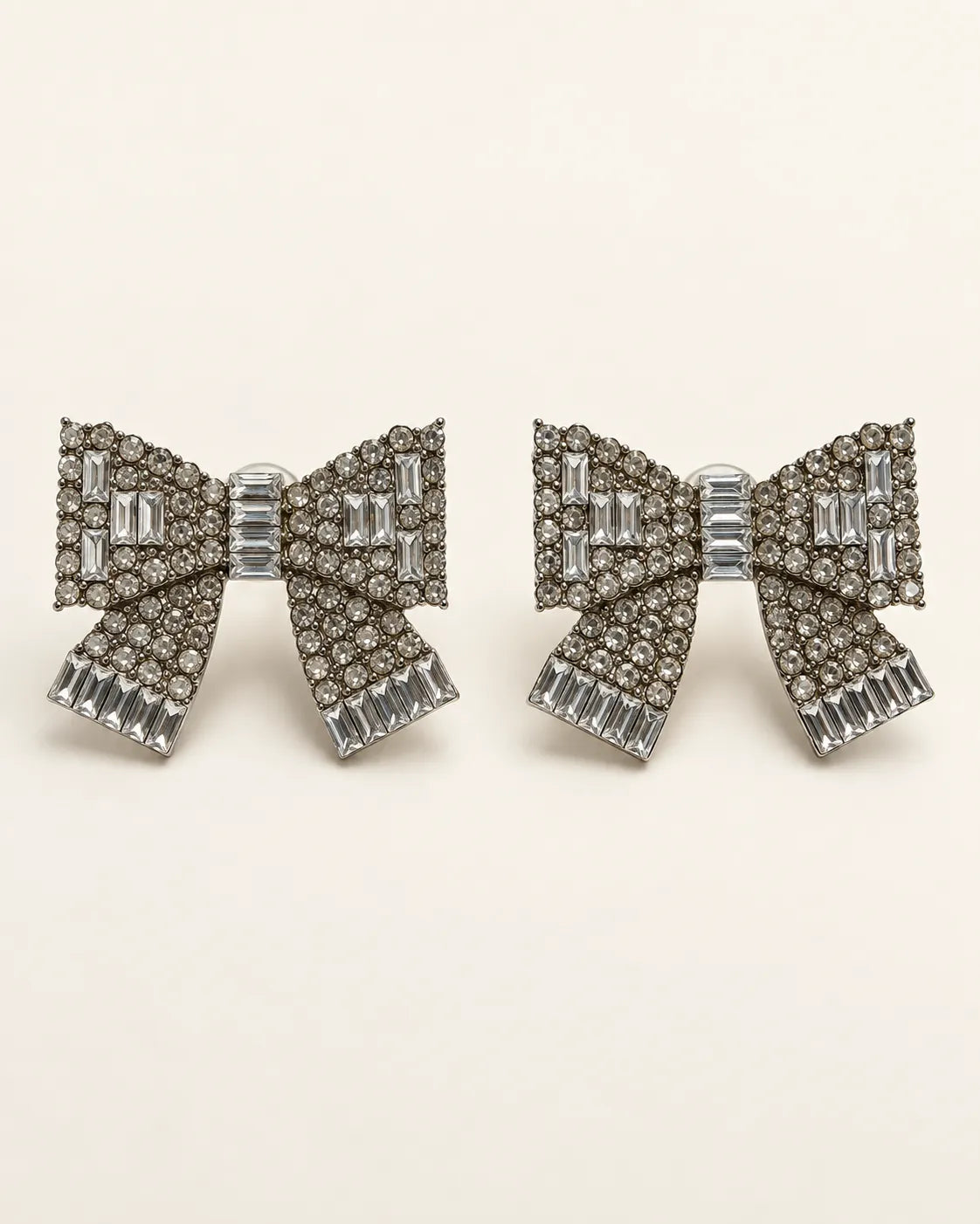 Large clear rhinestone bow stud earrings on a cream background