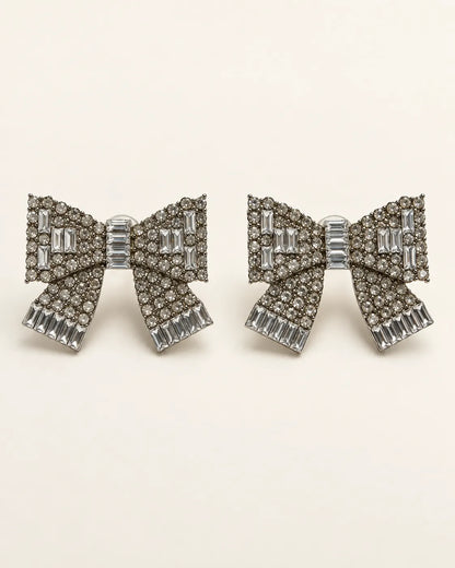 Large clear rhinestone bow stud earrings on a cream background