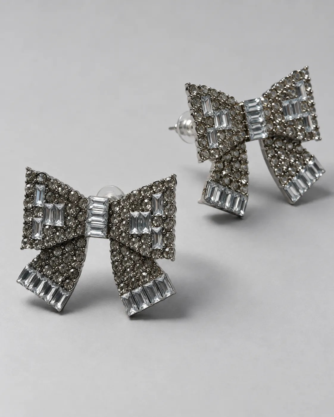 Angled view of the baguette and round rhinestone bow studs on grey