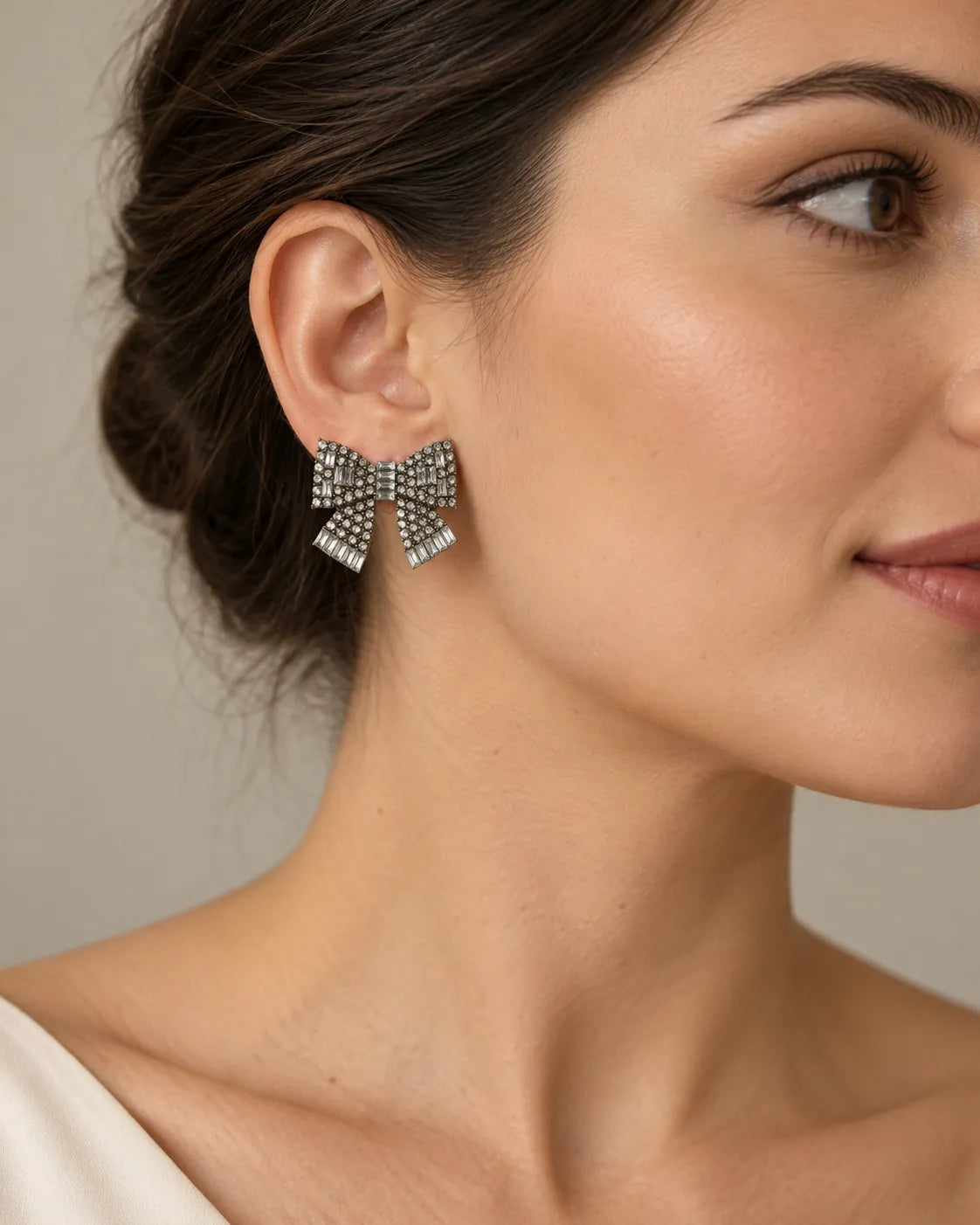 Side profile of a model with an updo wearing the clear rhinestone bow stud