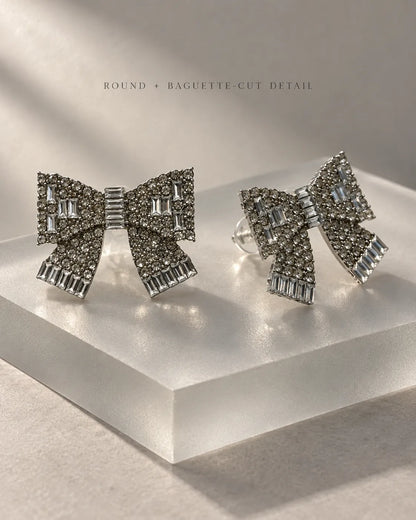 Clear rhinestone bow studs displayed on an acrylic block