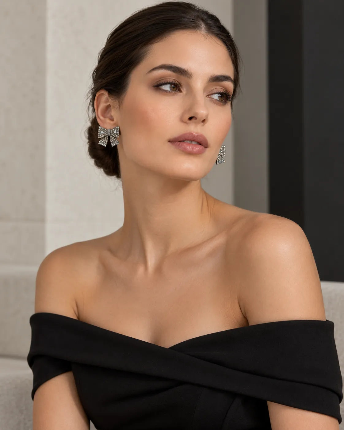 Model in a black off-shoulder top wearing the large bow stud earrings