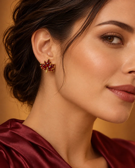 Model in a red top wearing the dark red crystal maple leaf stud