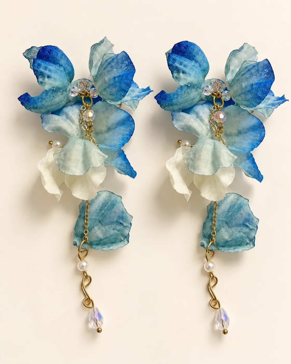 Blue and white fabric flower statement drop earrings on a cream background