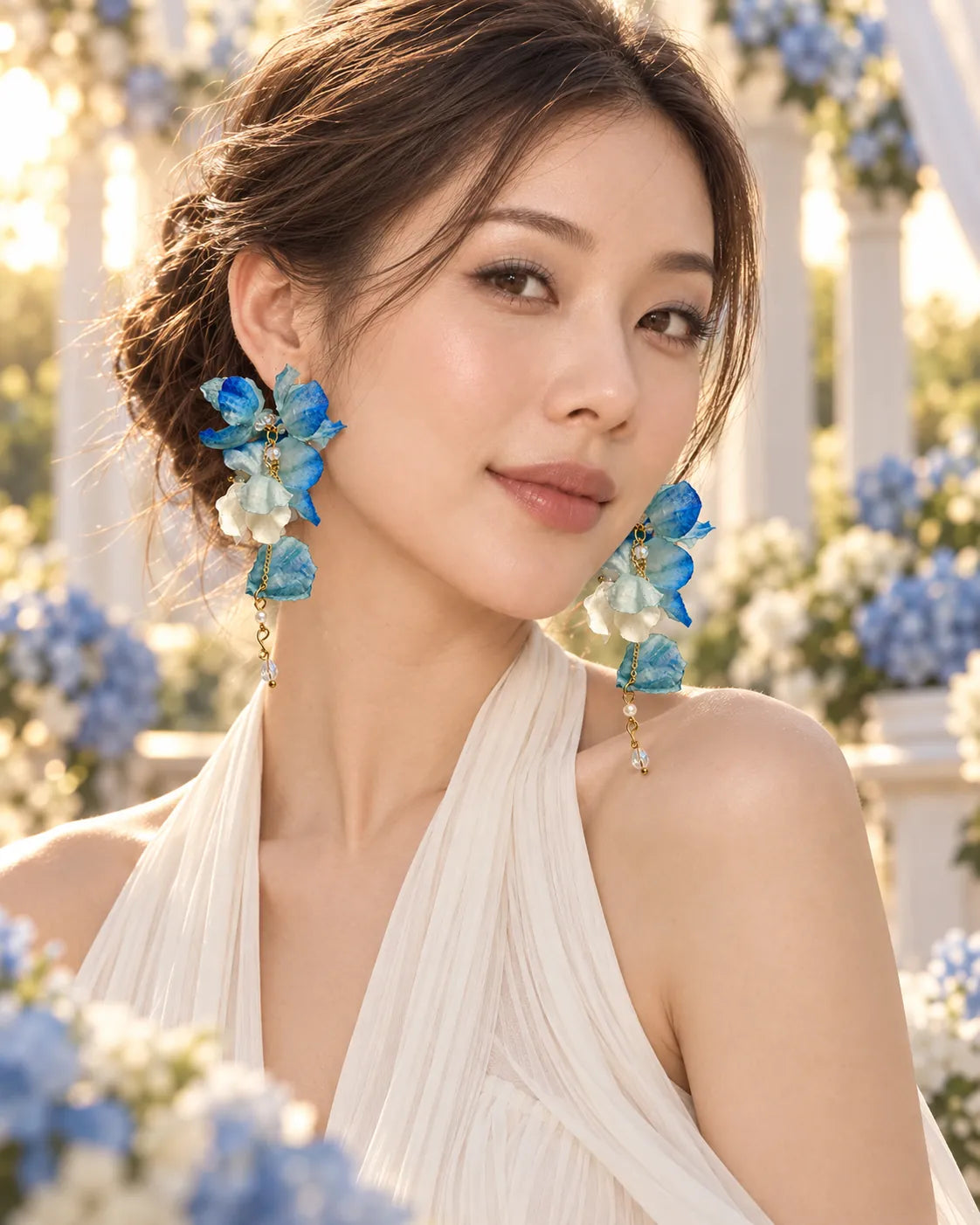 Model beside blue hydrangeas wearing the cobalt fabric flower drop earrings