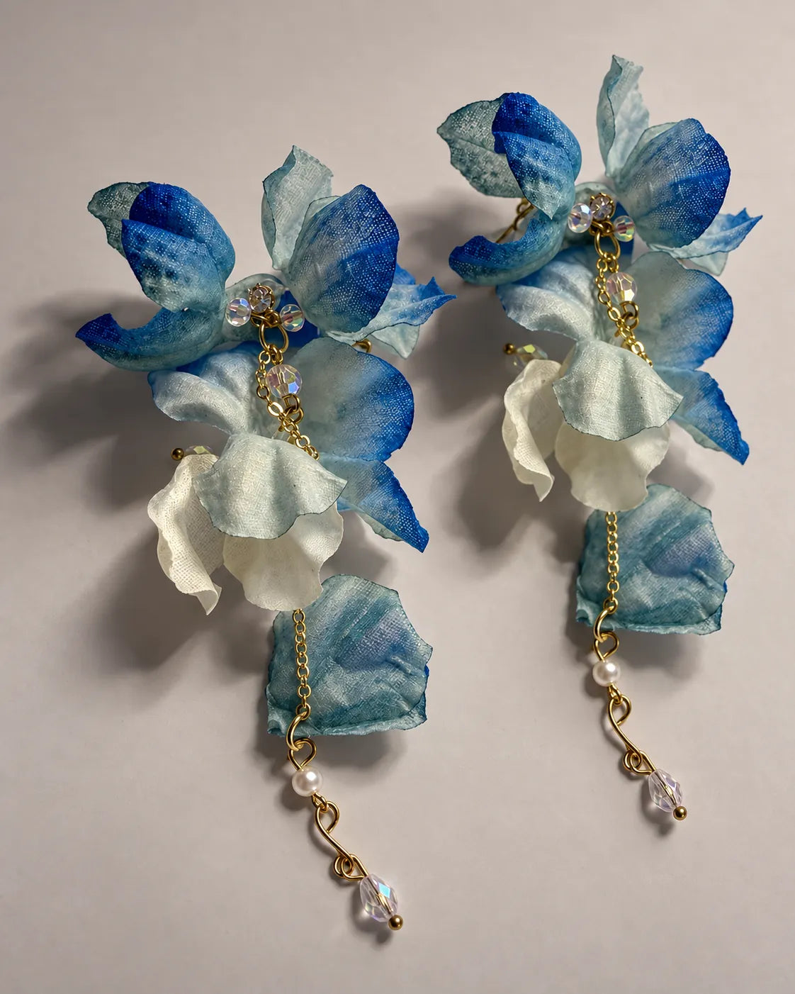 Pair of cobalt blue fabric petal drop earrings on a grey surface