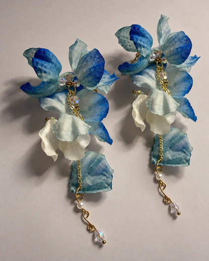 Pair of cobalt blue fabric petal drop earrings on a grey surface