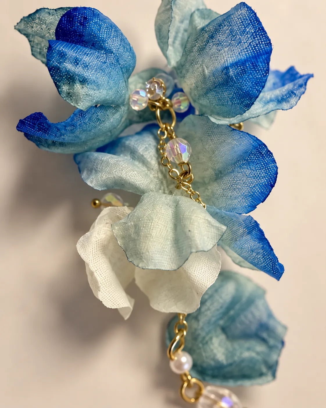 Close-up of the layered blue fabric petals and gold-tone crystal centre