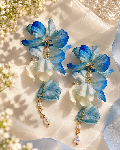 Blue flower drop earrings on satin surrounded by flowers