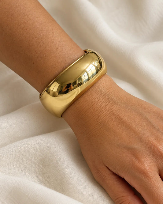 Wrist on white fabric wearing the domed gold cuff