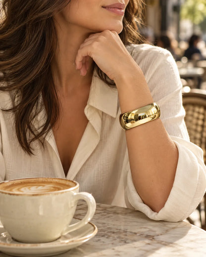Model in a white shirt at a cafe wearing the gold statement cuff