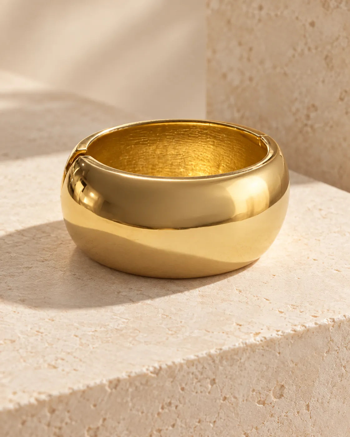 Gold domed cuff bracelet resting on a stone block