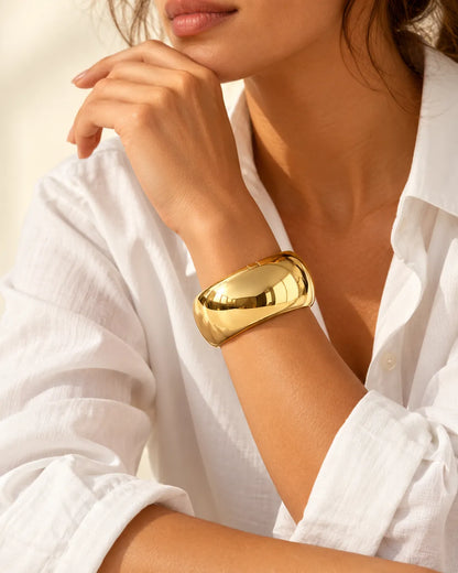 Model in a white shirt wearing the chunky gold cuff near her face