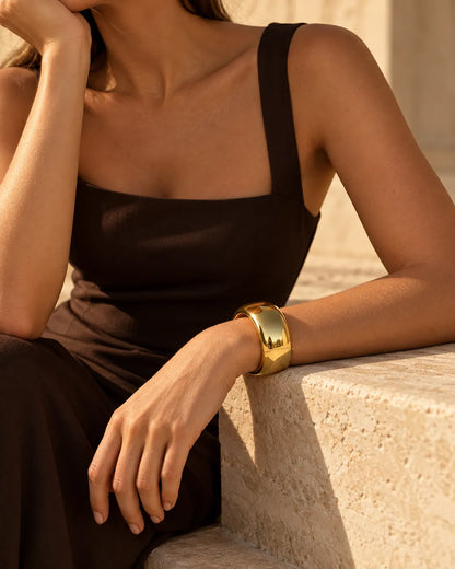 Model in a black dress wearing the polished gold cuff bracelet