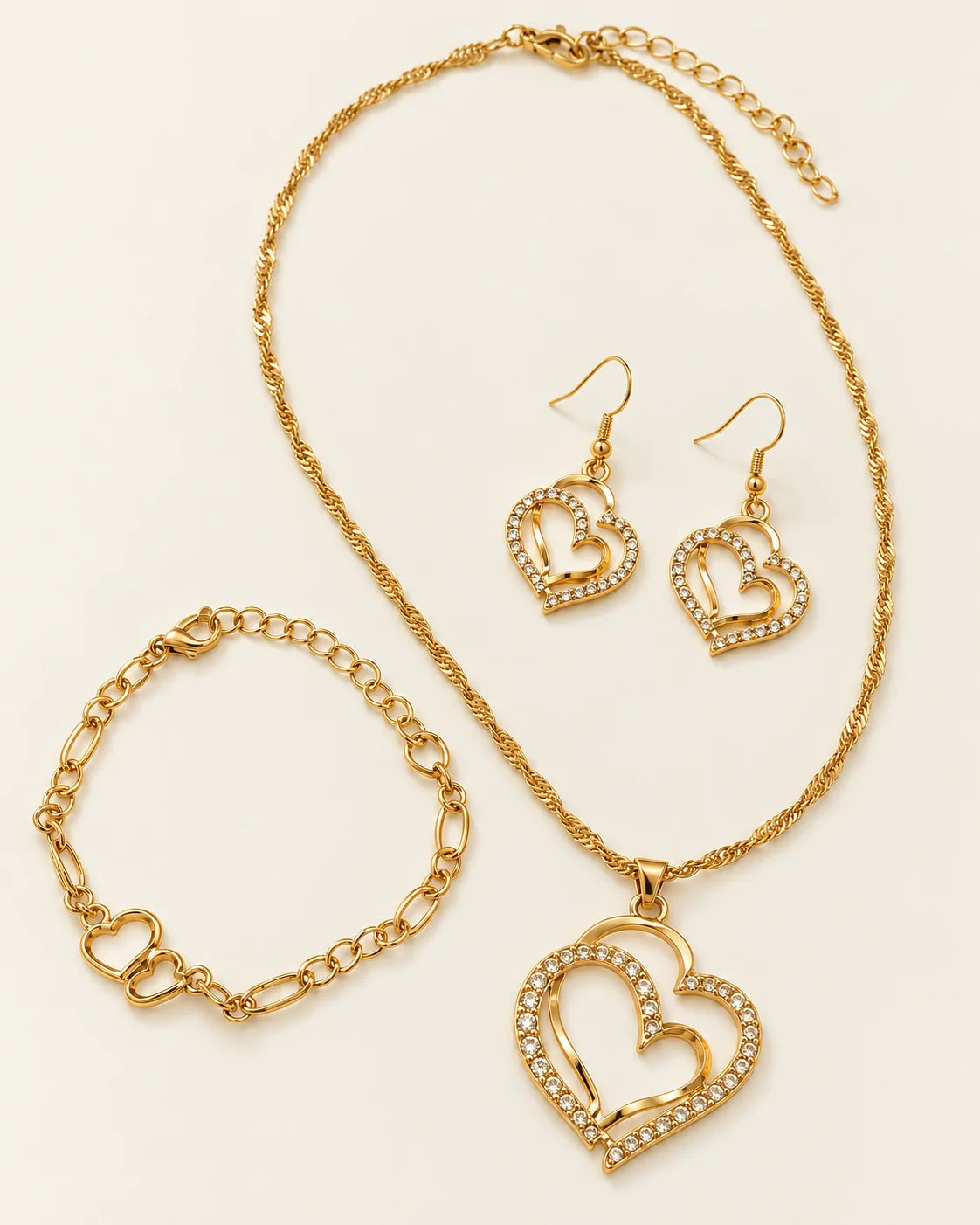 Everlinked gold double heart necklace, earrings and bracelet set laid flat on cream