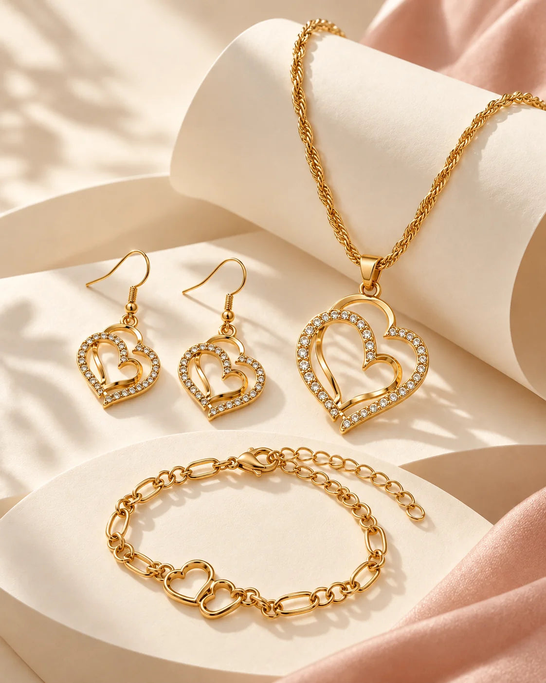 Gold double heart jewellery set styled on sculptural cream curves