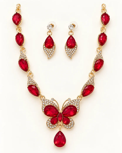 Papillon red crystal butterfly necklace and earring set in gold tone laid flat on cream
