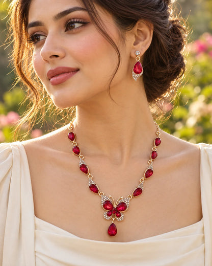 Woman in golden garden light wearing the red crystal butterfly necklace and earrings