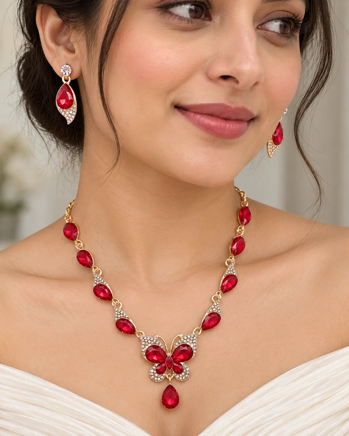 Woman wearing the red crystal butterfly necklace and earrings with an ivory off-shoulder top