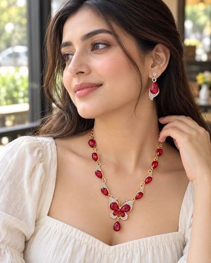 Woman in a café wearing the Papillon red butterfly necklace and teardrop earrings
