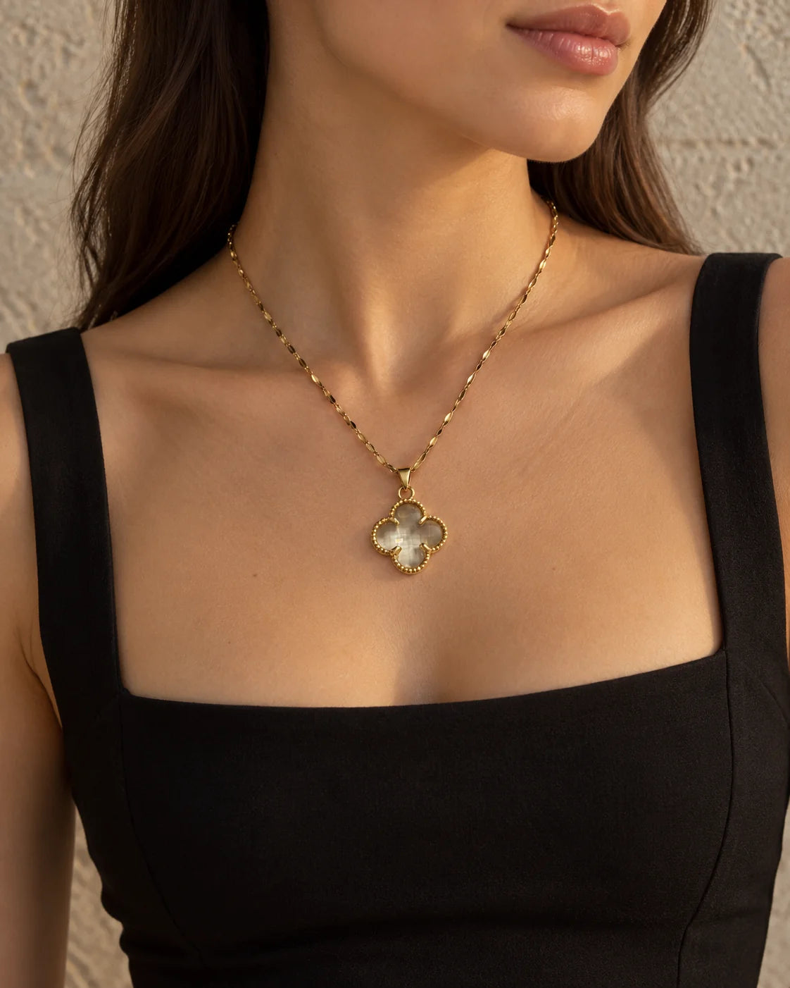 Fortuna clear clover necklace worn with a black square-neck dress