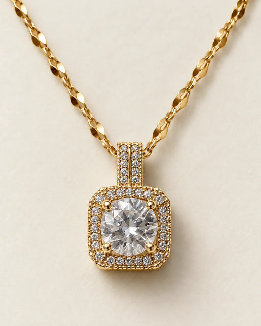Celeste gold cushion halo pendant with a round clear centre stone on a cream background