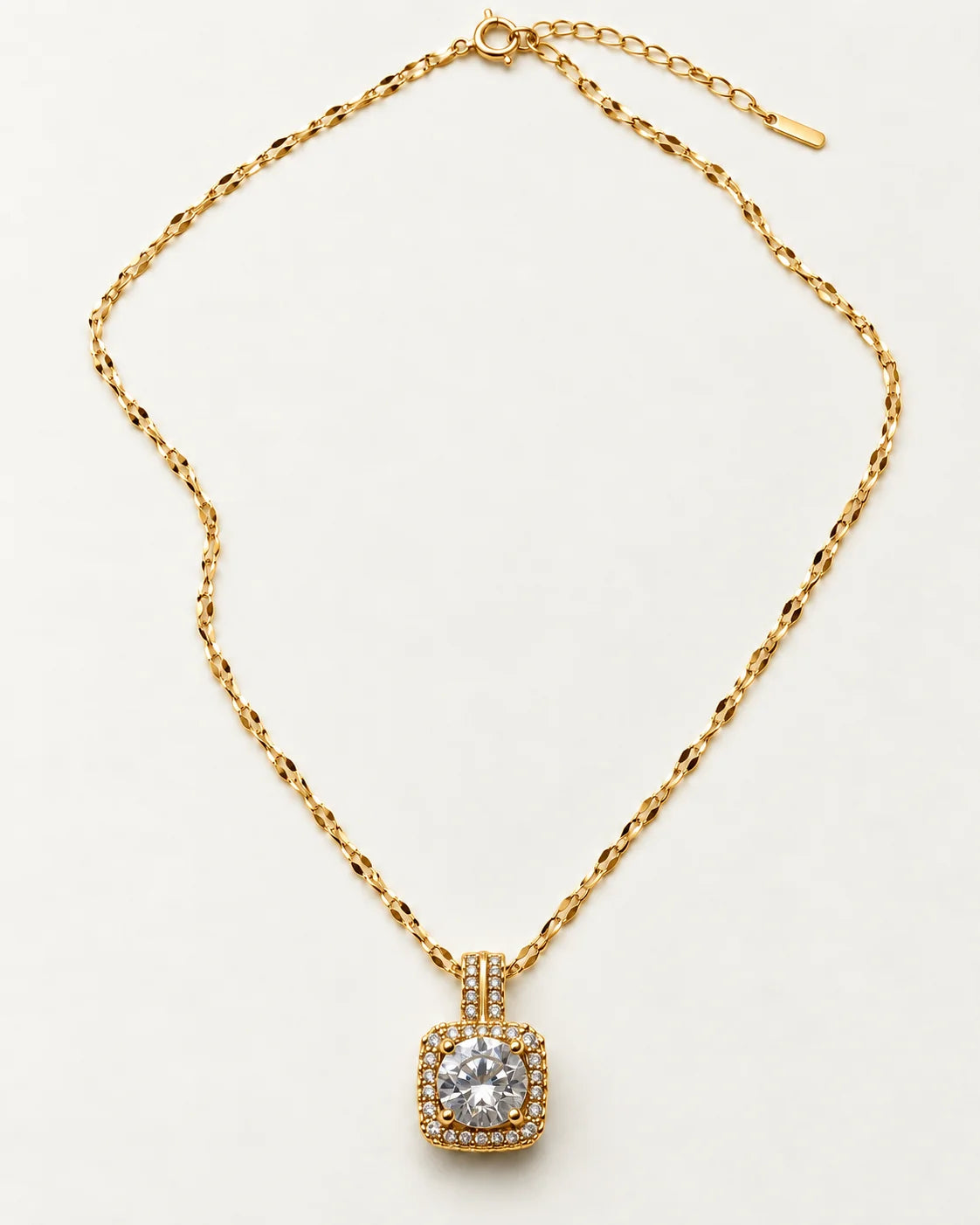 Full length of the Celeste gold cushion halo necklace laid flat with its extender chain