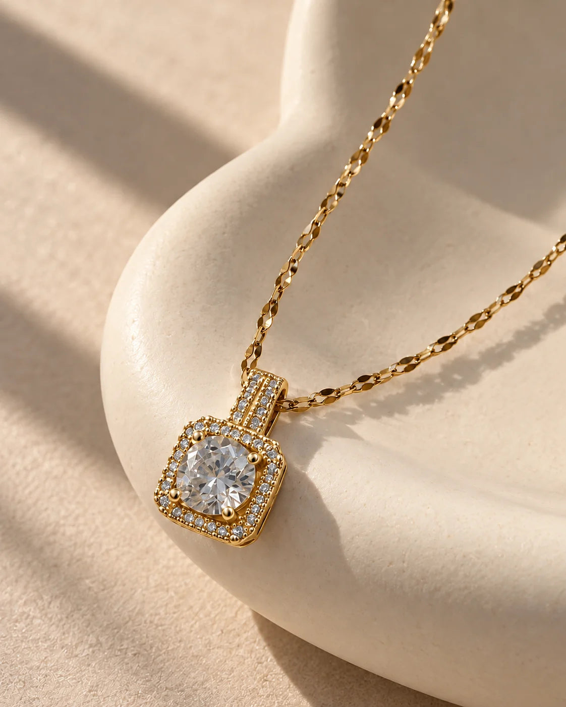 Celeste gold cushion halo pendant draped over a sculptural ivory curve