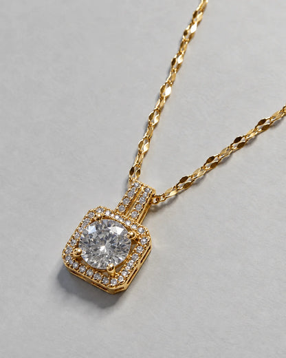 Celeste gold cushion halo pendant on a faceted link chain against soft grey