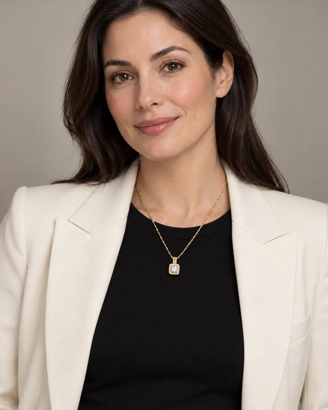 Model in a black top and ivory blazer wearing the Celeste gold halo pendant