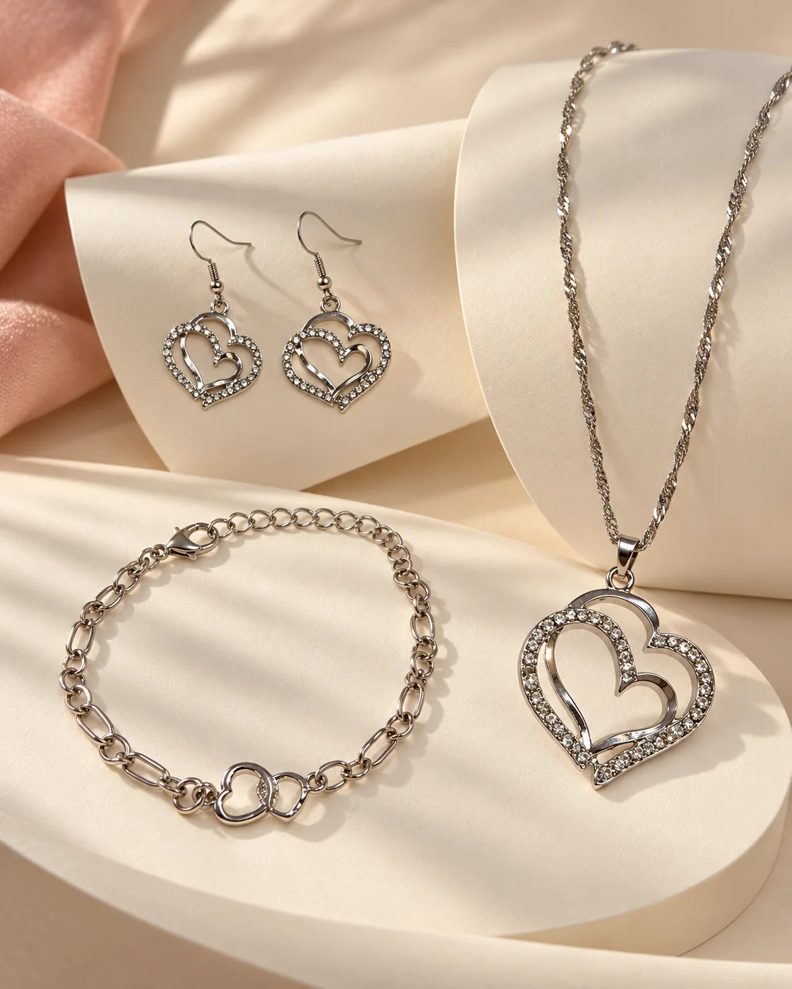 Silver double heart jewellery set styled on cream curves
