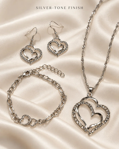 Silver-tone double heart necklace, earrings and bracelet on ivory satin