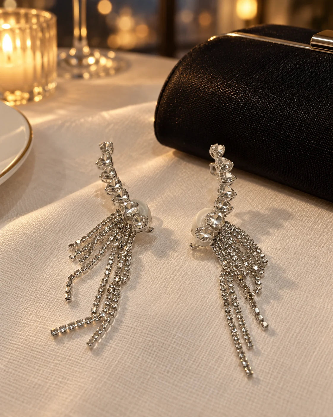 Silver heart ear climber earrings on evening linen beside a black clutch