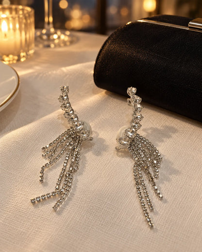 Silver heart ear climber earrings on evening linen beside a black clutch