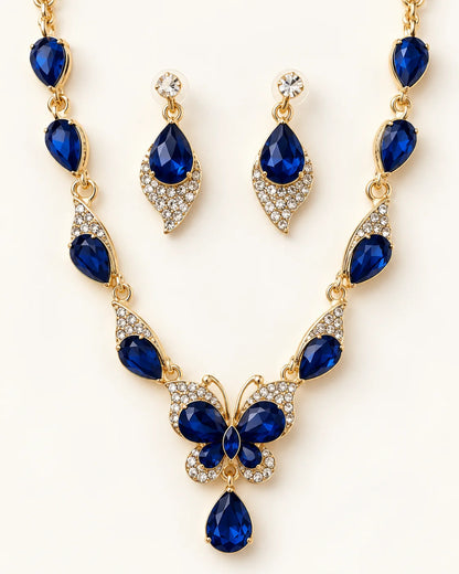 Papillon navy blue crystal butterfly necklace and earring set in gold tone laid flat on cream
