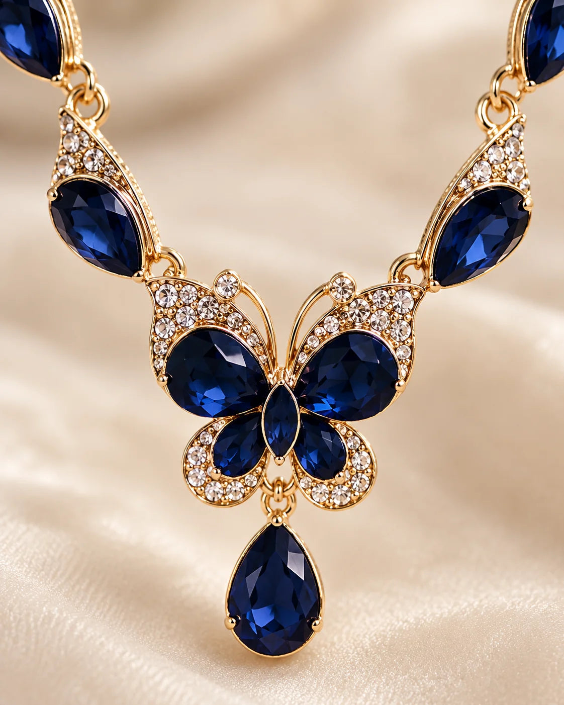 Close-up of the gold-tone butterfly pendant set with navy blue crystals and clear rhinestones