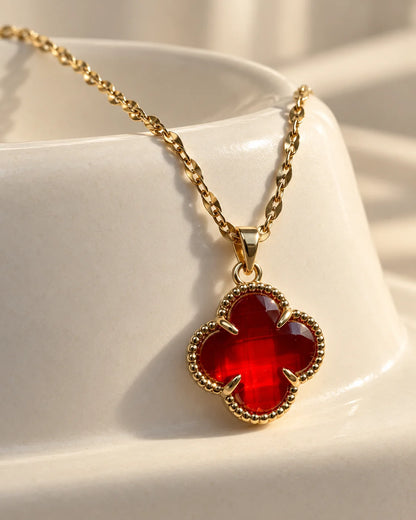 Fortuna cherry red clover pendant resting on an ivory ceramic dish